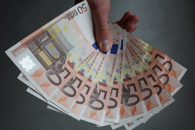 Mano ofreciendo billetes de euro: donación de dinero a un hijo